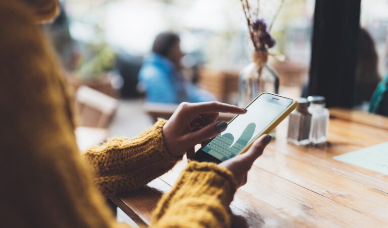 Girl hold in hand empty screen mobile phone, person type message on smartphone in cafe, relax tourist travels plan trip, hipster enjoy journey in cityscape, lifestyle holiday concept, internet online